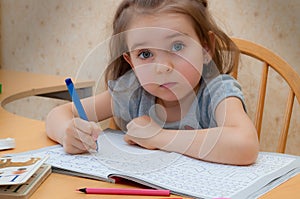 Baby girl sitting writing at the table