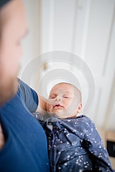 Baby Girl is Sleeping in Her Blue Onesie While Dad Admires Her