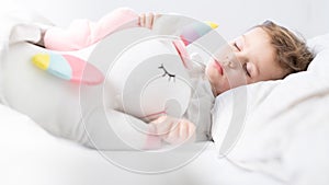 Baby girl sleeping with her unicorn. Close up.