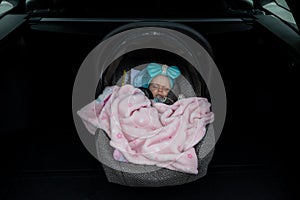 Baby girl sleeping in a safety child car seat. 3 months old baby girl. Protection concept, safety, and security