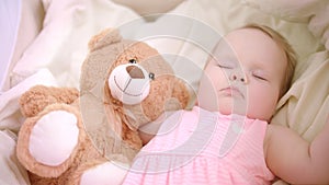Baby girl sleeping with toy in crib. Sweet bedtime. Little girl dream in bed