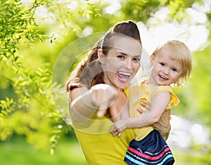 Baby girl and smiling mother pointing in camera