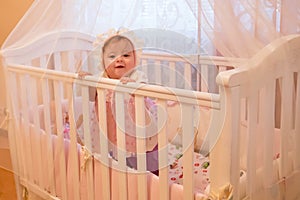 Baby girl standing in her crib.