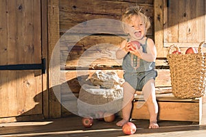 Baby Girl stands and Smiles near Wooden Barn