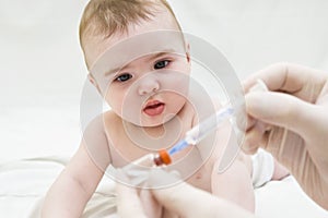 Baby girl is starring on syringe with vaccine