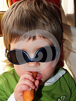 Baby girl with sunglasses and carrot