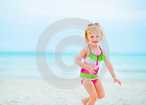 Baby girl in sunglasses playing on beach