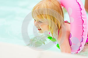 Baby girl with swim ring swimming in pool