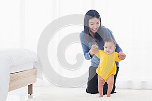 Baby girl taking first steps learning to walk with mom