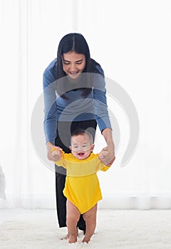 Baby girl taking first steps learning to walk with mom