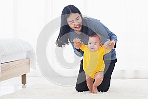 Baby girl taking first steps learning to walk with mom