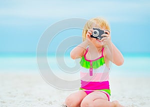 Baby girl taking photo on beach