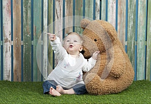 Baby girl with teddy bears seated on grass