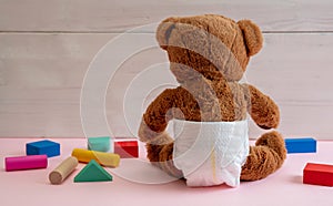 Baby girl  teddy wearing diaper playing with colorful wooden blocks on pink color floor