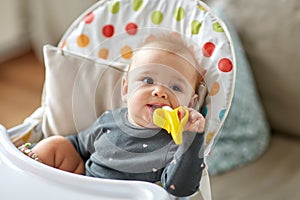 Baby girl with teether toy in highchair at home