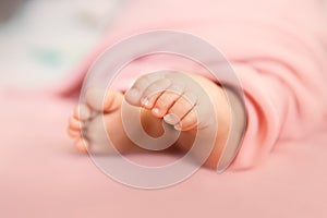 Baby girl tiny toes on pink background in a selective focus, maternity and babyhood concept