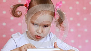 Baby girl touches finger the touchscreen of the smartphone and loads applications.