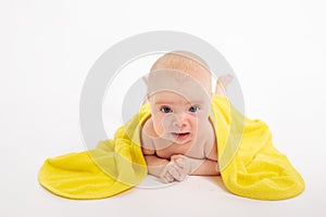 Baby girl in a towel after bathing on a white isolated background looks at the camera, baby 3-6 months, space for text