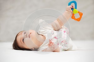 Baby girl with a toy lying on blanket indoors