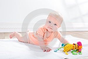 Baby girl with toy, lying on the floor