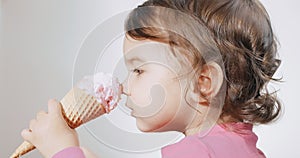 Baby girl tries and fails to eat her first ice cream cone.