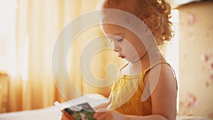 Baby girl tries to read little book at home