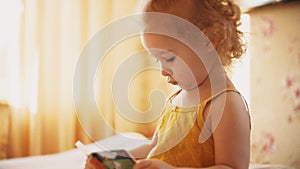 Baby girl tries to read little book at home