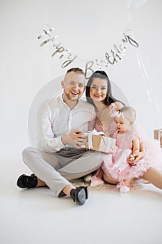 Baby girl unwrapping birthday present with happy parents