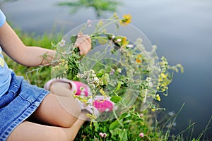 Baby girl walks on a river wreath of wild flowers