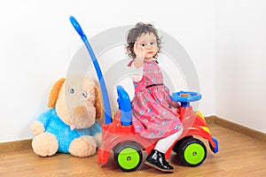 Baby girl waving goodbye on a toy car