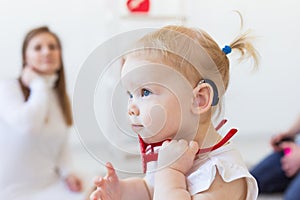 Baby girl wearing a hearing aid. Disabled child, disability and deafness concept.