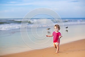 Baby girl wearing pink shirt and diaper on beach