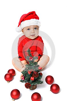 Baby girl wearing a Santa Claus hat and Christmas tree