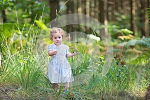 Baby girl wearing a white dress in sunny autumn park
