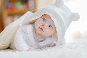 Baby girl wearing white towel or winter overal in white sunny bedroom