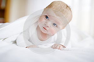 Baby girl wearing white towel or winter overal in white sunny bedroom