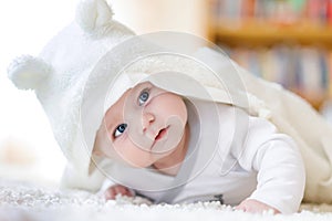 Baby girl wearing white towel or winter overal in white sunny bedroom