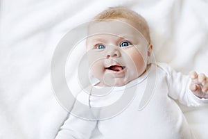 Baby girl wearing white towel or winter overal in white sunny bedroom