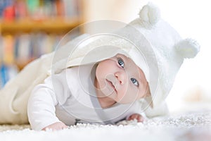 Baby girl wearing white towel or winter overal in white sunny bedroom