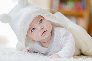 Baby girl wearing white towel or winter overal in white sunny bedroom