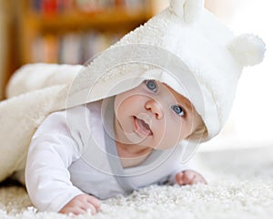 Baby girl wearing white towel or winter overal in white sunny bedroom