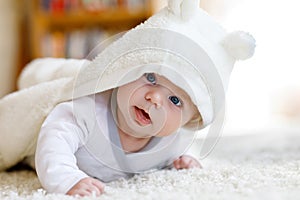 Baby girl wearing white towel or winter overal in white sunny bedroom