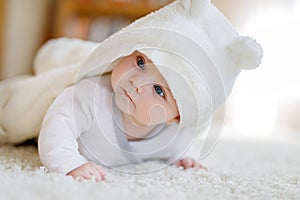 Baby girl wearing white towel or winter overal in white sunny bedroom