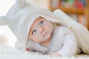 Baby girl wearing white towel or winter overal in white sunny bedroom