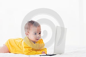 Baby girl wearing a yellow dress typing hands on laptop computer keyboard