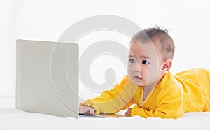 Baby girl wearing a yellow dress typing hands on laptop computer keyboard