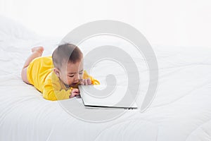 Baby girl wearing a yellow dress typing hands on laptop computer keyboard