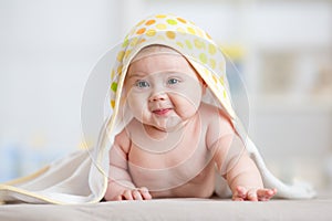 Baby girl wrapped towel in children nursery room. Newborn kid relaxing in bed after bath or shower.