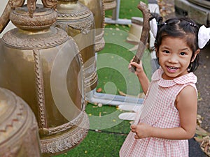 A baby girl, 3 years old, enjoys ringing big temple bells as the sound of the bell is considered auspicious photo