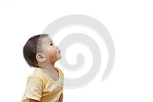 A baby girl with yellow clothes is looking up to the left side